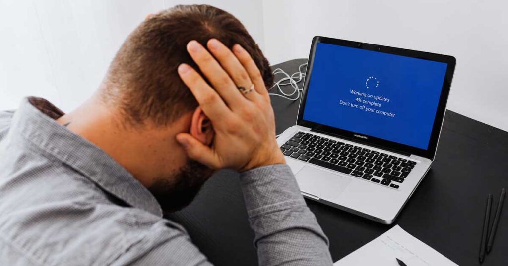 Frustrated computer user waiting on a Windows update screen while troubleshooting update problems